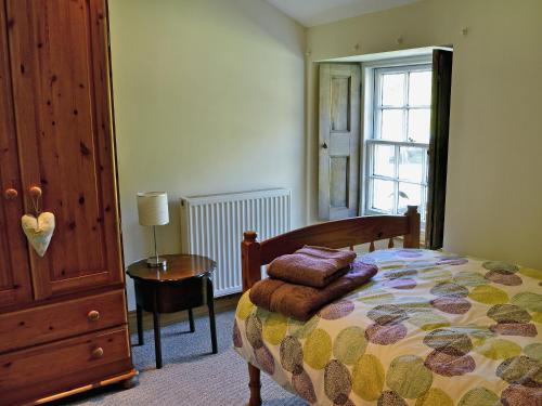 CarronbridgeWaulkmill Cottage的一间卧室配有一张床、一张桌子和一个窗户。