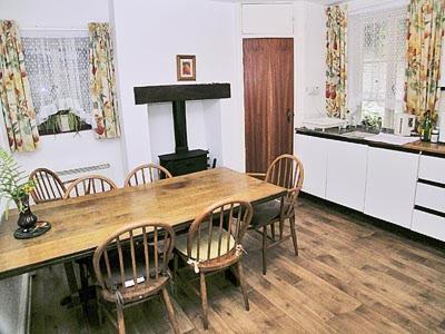 WithycombeTacker Street Cottage的厨房配有木桌、椅子和炉灶。