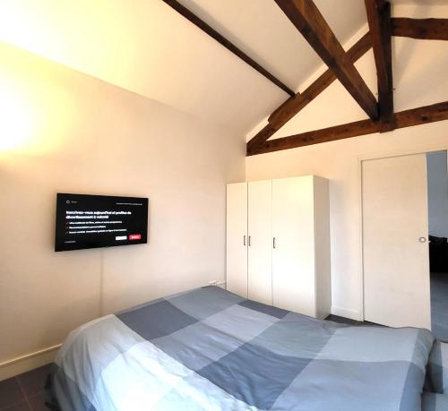奥尔日河畔于维西Residence du Parc des Grottes - N 3的卧室配有一张床,墙上配有电视。