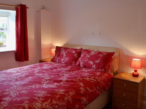 Caldwell汤姆斯小屋度假屋的一间卧室配有一张带红色床单的床和一扇窗户。