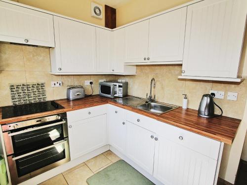 内瑟·斯托威Quantock Hideaway的厨房配有白色橱柜和水槽