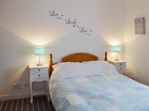 斯卡伯勒Beach Walk Cottage的一间卧室配有一张带2个床头柜和2盏灯的床。