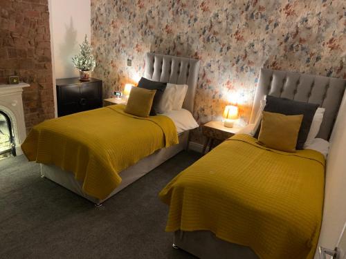 艾纯查姆46 Ashfield Rd, Altrincham的一间卧室设有两张带黄床单的床和壁炉