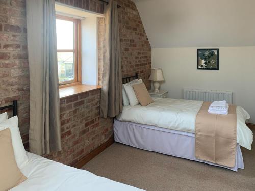 North Somercotes格兰纳里度假屋的一间卧室设有两张床和砖墙