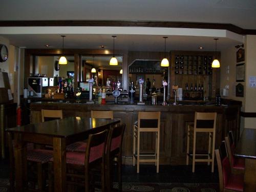 罗瑟勒姆The Fitzwilliam Hotel的餐厅内的酒吧配有桌椅