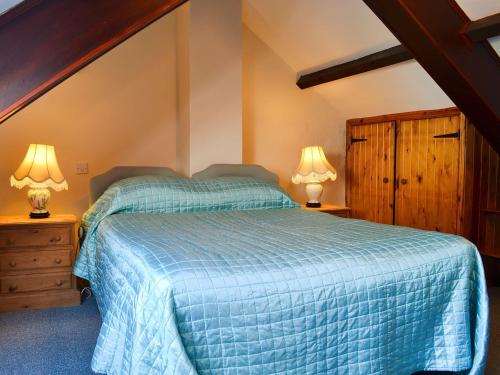 Bardon Mill菲尔布里奇度假屋的一间卧室配有一张床,并在床头柜上配有两盏灯