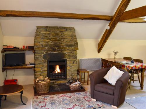 Arthog伊尔汉乡村别墅的客厅设有石制壁炉和椅子