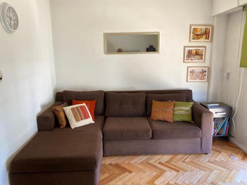 布宜诺斯艾利斯Acogedor departamento en Caballito的客厅配有带色彩缤纷枕头的棕色沙发