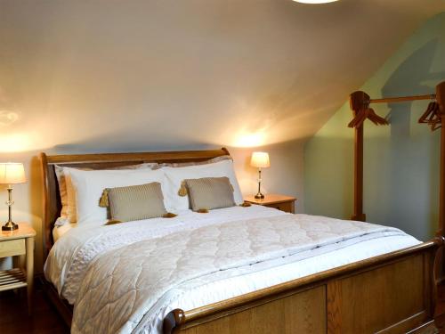格兰奇农庄小屋的一间卧室配有一张带两盏灯的大型白色床。