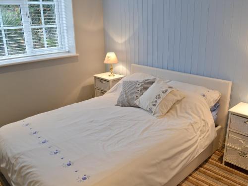 Chacewater小度假屋的卧室内的一张带白色床单和枕头的床