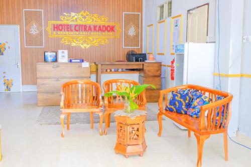 哥打巴鲁Citra Kadok Hotel & Banquet Hall的一间设有三把椅子、一张桌子和一台冰箱的房间