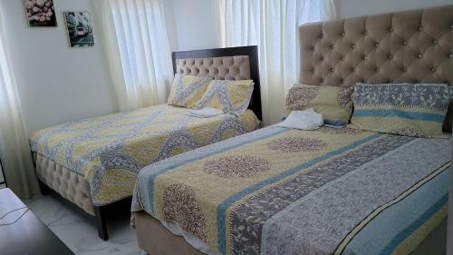 佩德纳莱斯Madome Aparta Hotel的一间卧室配有两张床和床头板