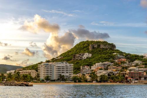 辛普森湾Atrium Beach Resort and Spa St Maarten a Ramada by Wyndham的水体旁的山丘上的度假胜地