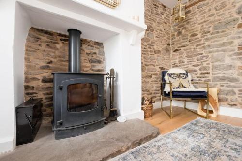 LlanigonLuxury Cottage near Hay-on-Wye的客厅设有石头壁炉,配有椅子