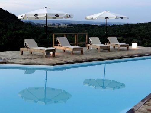 塞拉纳镇Villa Serrana - Mesón de las cañas的游泳池顶部设有椅子和遮阳伞