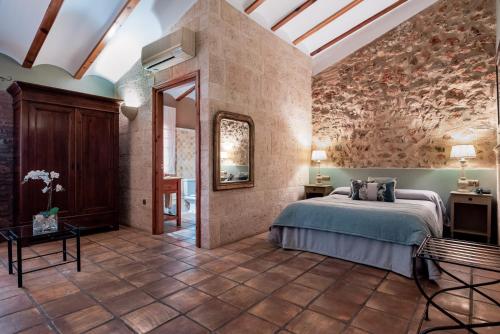 Villalonga卡萨巴贝尔酒店的石墙客房的卧室配有一张床
