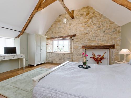 阿克斯明斯特海尔维斯特瓦特度假屋的卧室配有一张白色的大床和石墙