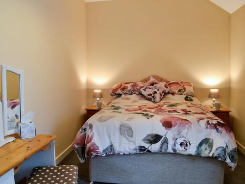 GoosehamDoves Den的一间卧室配有一张床和一张带两盏灯的书桌。