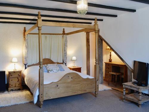 南莫尔顿Conifers的一间卧室设有木天蓬床和电视。