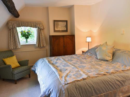 奇平卡姆登罗斯迎宾小屋的卧室配有床、椅子和窗户。
