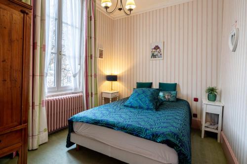 布尔日Le Cedre Bleu的一间卧室配有一张带蓝色床单的床和一扇窗户。