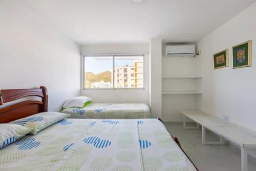 圣玛尔塔Apartamento Tacoa 703的一间卧室设有两张床、一张桌子和一个窗口。