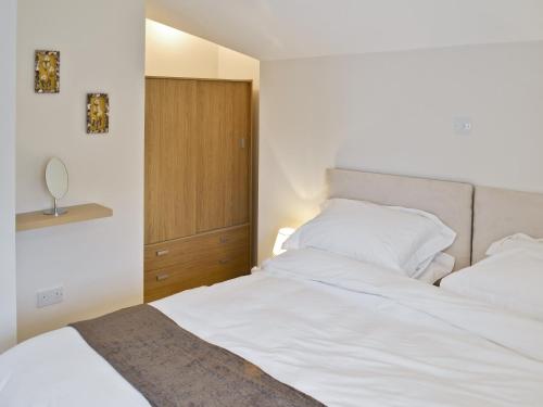 BirchBaytree Cottage 2的卧室配有白色的床和木制橱柜。