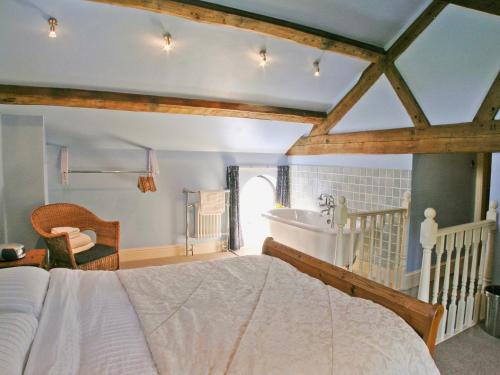 Helsby老马厩乡村别墅的一间卧室配有一张床、一个浴缸和一个水槽