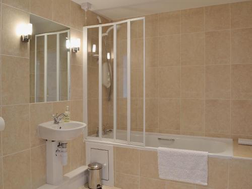 Llanwrda亚斯塔贝尔乡村别墅的一间带水槽、浴缸和镜子的浴室