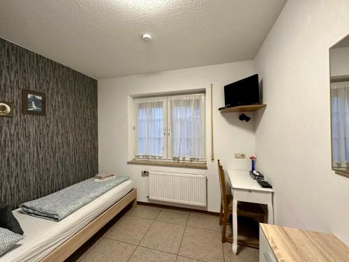 林德拉尔Hotel Landhaus Köln的一间卧室配有一张床和一张书桌及电视