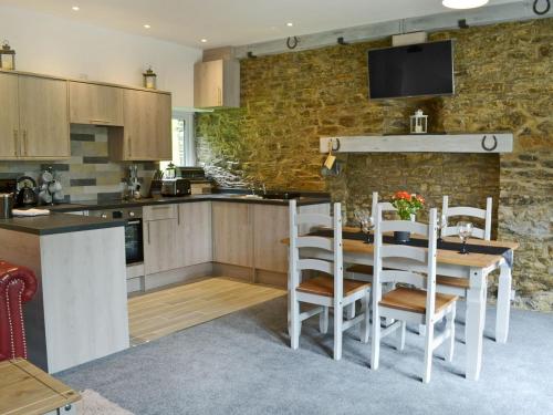 Saint CleerRosecraddoc Manor - Stable的厨房配有桌椅和石墙