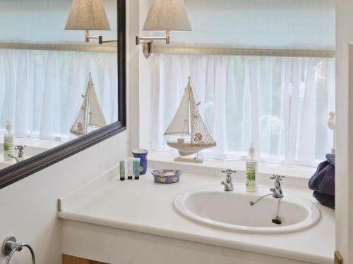 MaidensLearig Cottage的浴室水槽设有镜子,窗户上设有帆船