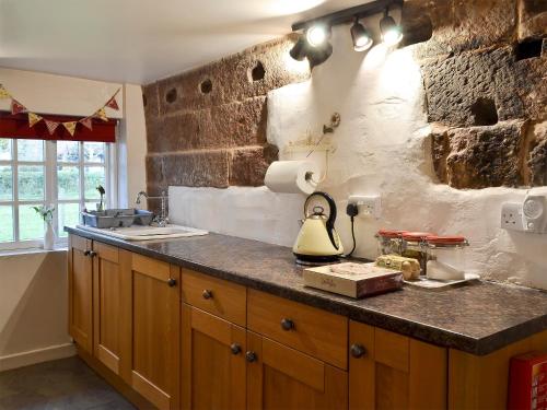 Hale乔尔德黑尔乡村度假屋的厨房设有石墙和带台灯的台面