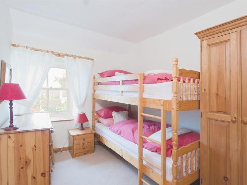 克罗索恩Holly Cottage的一间卧室配有两张双层床和粉红色床单