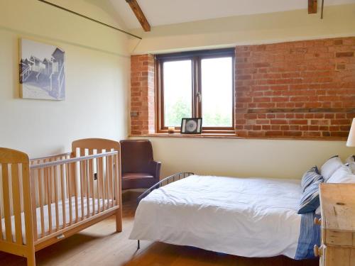 斯肯索普鹧鸪谷仓度假屋的一间卧室设有一张婴儿床和砖墙