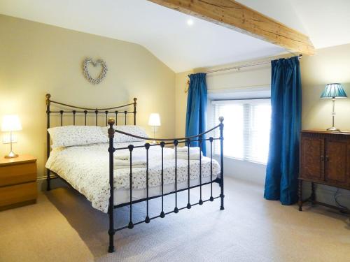 皮克林豪加斯乡村别墅的一间卧室配有一张带蓝色窗帘的床和一扇窗户