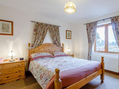 Runcton HolmeLintel Barn - E5253的一间卧室设有一张木床和一个窗户。