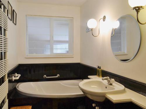 LlangennyTegfan的一间带水槽、浴缸和镜子的浴室