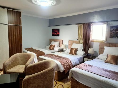 法尤姆فاكانزا شقة فندقية مفروشة- vacanze的酒店客房,设有三张床和椅子