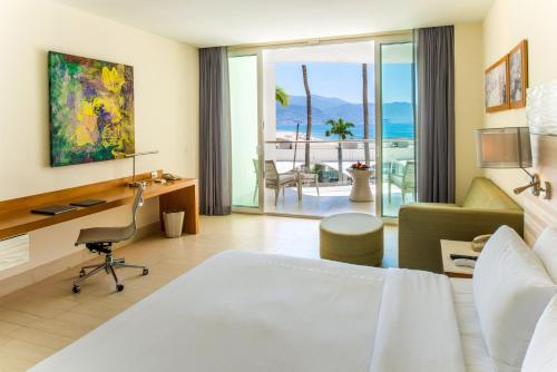 巴亚尔塔港Krystal Grand Puerto Vallarta - All Inclusive的酒店客房配有一张床、一张桌子和一把椅子。