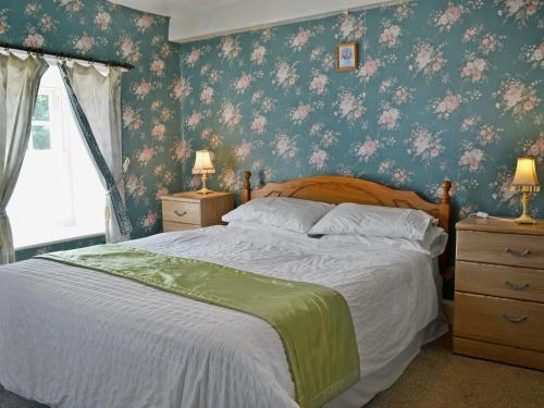 LlandudwenNyffryn Bella的一间卧室配有一张带花卉壁纸的大床