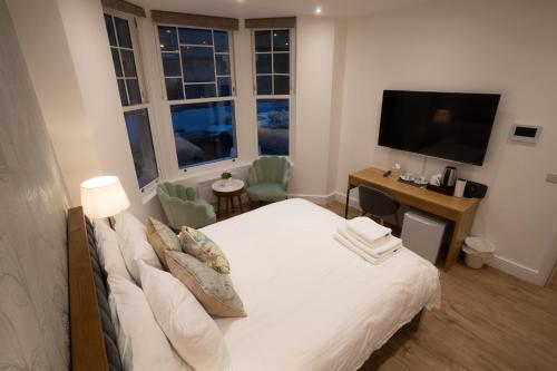 伦敦The Avonmore Olympia的卧室配有白色的床和电视。