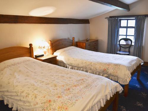 GarrigillHigh Windy Cottage的一间卧室设有两张床和窗户。
