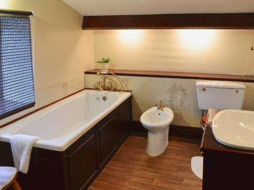 GarrigillHigh Windy Cottage的带浴缸、卫生间和盥洗盆的浴室