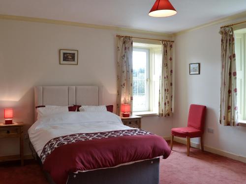 KirtlebridgeBonshawside Farmhouse的一间卧室配有一张大床和一张红色椅子