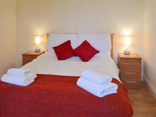 High Halstow干草谷仓乡村别墅的一间卧室配有一张带红色枕头的床和两盏灯。