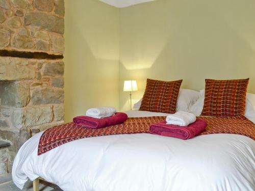 LlandybieThe Mill Farmhouse的一间卧室配有一张带红色枕头的大床
