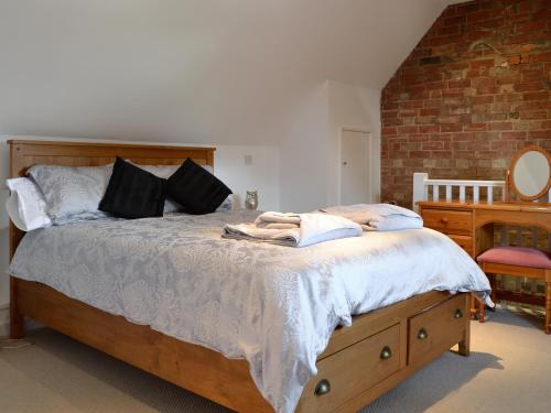 Alderton谷仓度假屋的一间卧室设有一张带砖墙的大床