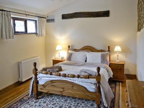 West BucklandHorseshoes - E5369的一间卧室配有一张木床、两盏灯和两张桌子