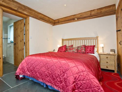 Little Petherick里尼哈伊酒店的一间卧室配有一张红色棉被的床